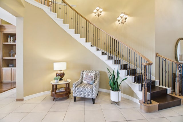 staircase with built in features, tile patterned flooring, a high ceiling, and baseboards