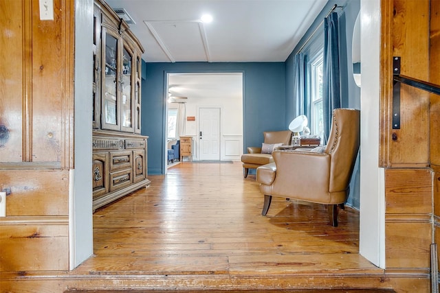 corridor featuring visible vents, light wood-style flooring, and a decorative wall
