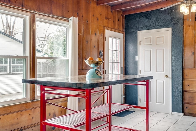 kitchen with beamed ceiling, wood walls, and light tile patterned floors