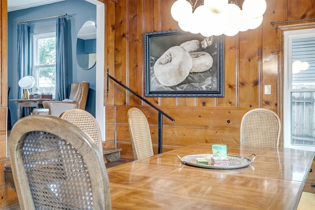 dining space with an inviting chandelier and wooden walls