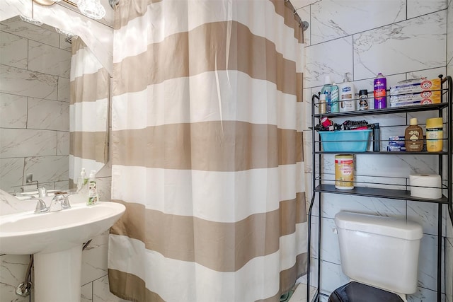 full bathroom featuring a shower with shower curtain, tile walls, toilet, and stone wall