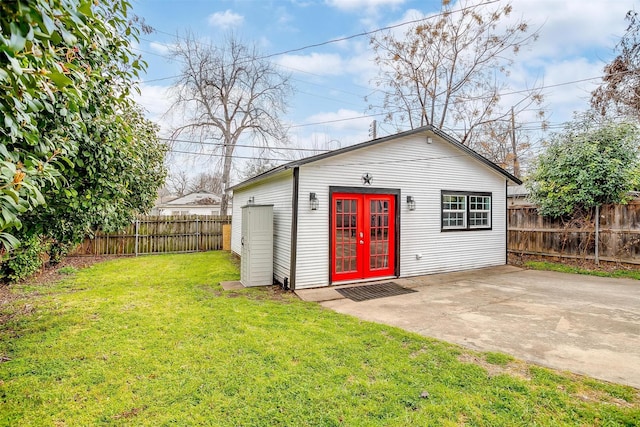 view of outdoor structure with a fenced backyard, french doors, and an outbuilding