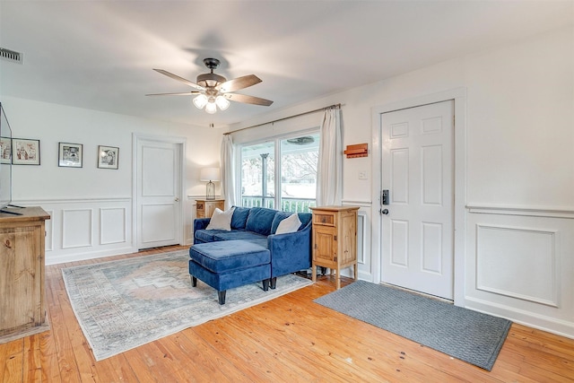 entryway featuring a wainscoted wall, visible vents, a decorative wall, light wood-style floors, and a ceiling fan