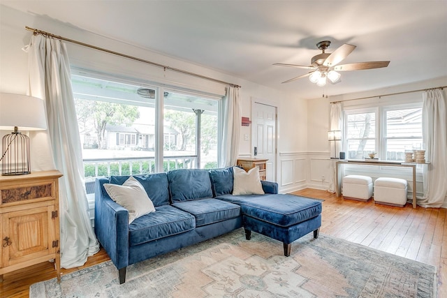 living area featuring a wainscoted wall, ceiling fan, hardwood / wood-style floors, and plenty of natural light