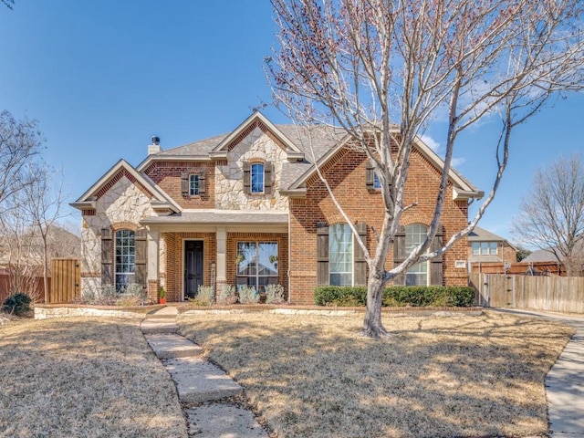 view of front of home featuring stone siding, a gate, fence, and brick siding