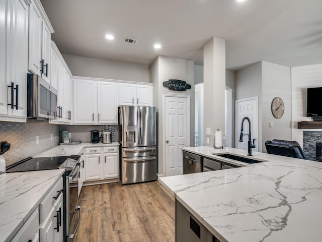 kitchen with light stone counters, a sink, visible vents, appliances with stainless steel finishes, and tasteful backsplash