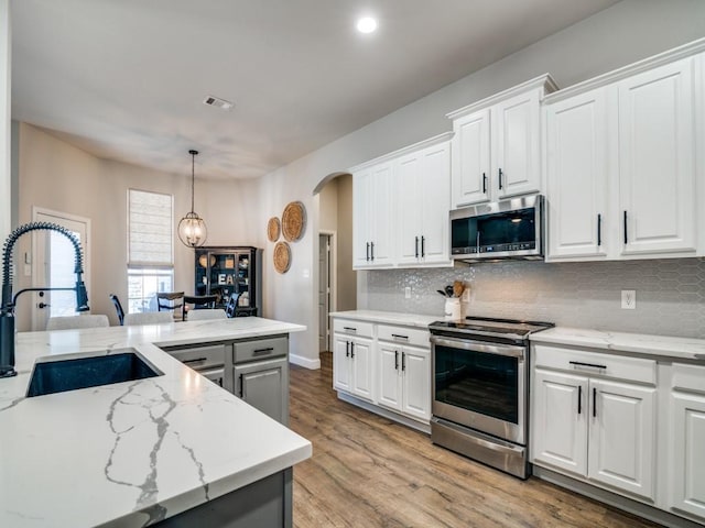 kitchen with arched walkways, tasteful backsplash, visible vents, appliances with stainless steel finishes, and a sink