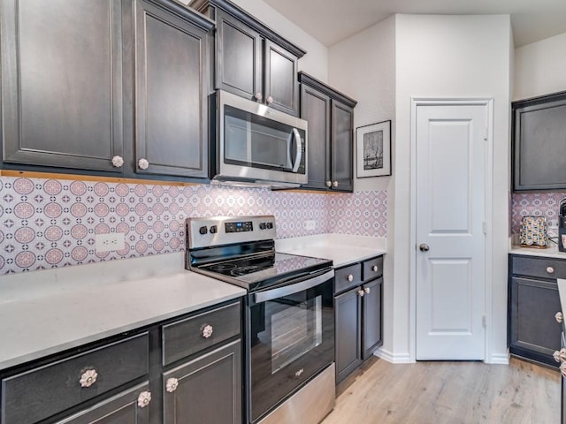 kitchen with stainless steel appliances, backsplash, light countertops, and light wood-style flooring