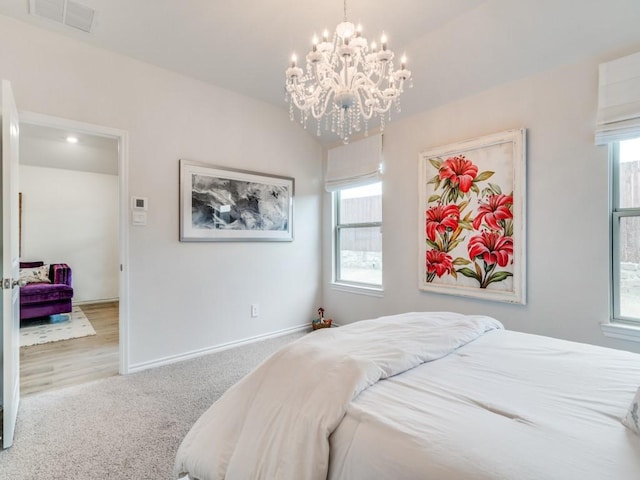 carpeted bedroom featuring an inviting chandelier, baseboards, multiple windows, and visible vents