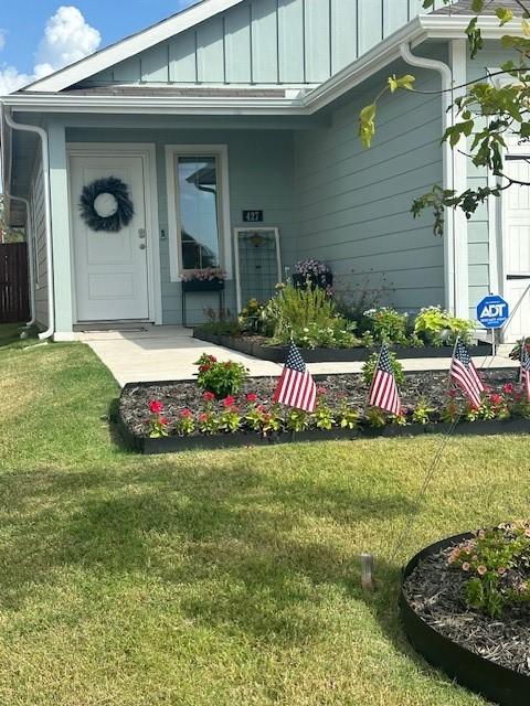 property entrance featuring a yard, a porch, and board and batten siding