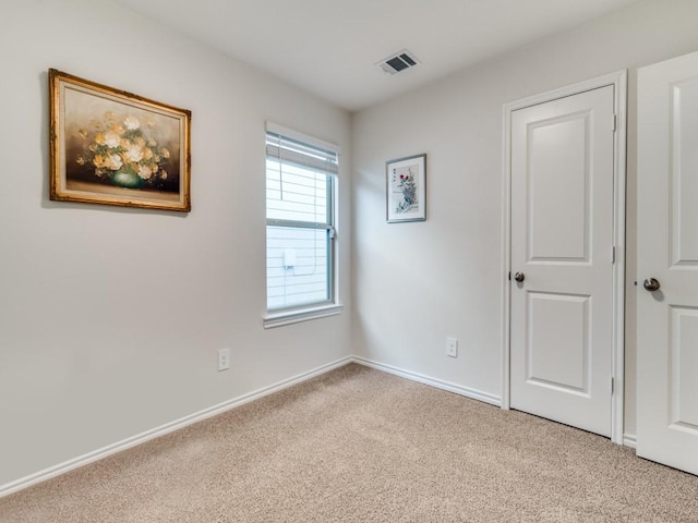 carpeted spare room featuring visible vents and baseboards