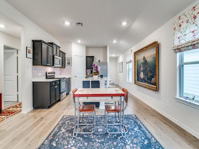 dining room with light wood-type flooring, visible vents, and baseboards