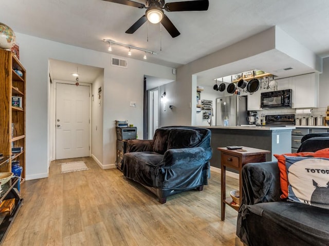 living room with light wood finished floors, baseboards, visible vents, and a ceiling fan