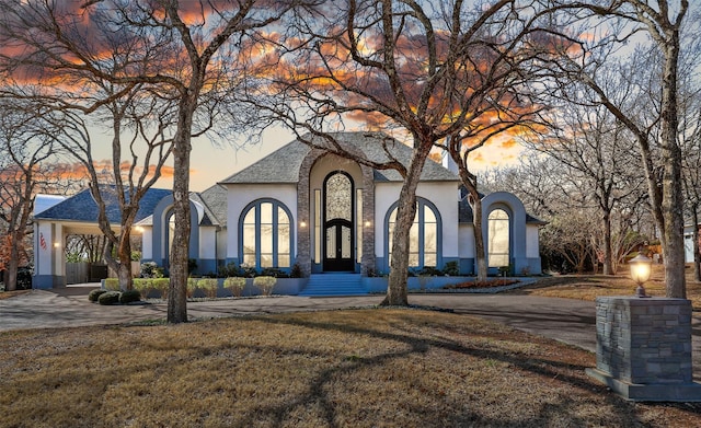 view of front of house featuring driveway, a yard, and stucco siding