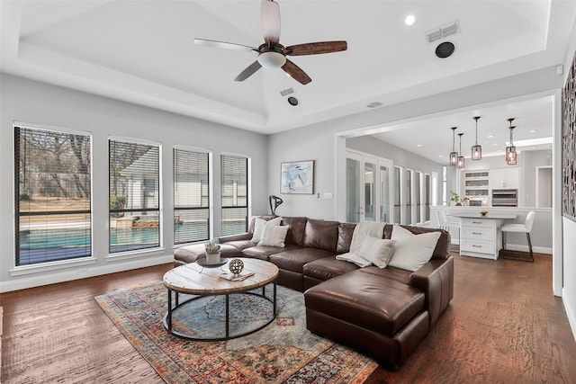 living room with recessed lighting, a raised ceiling, visible vents, dark wood-type flooring, and ceiling fan