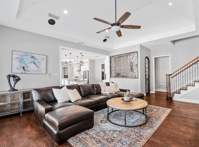 living room with stairway, visible vents, and a raised ceiling