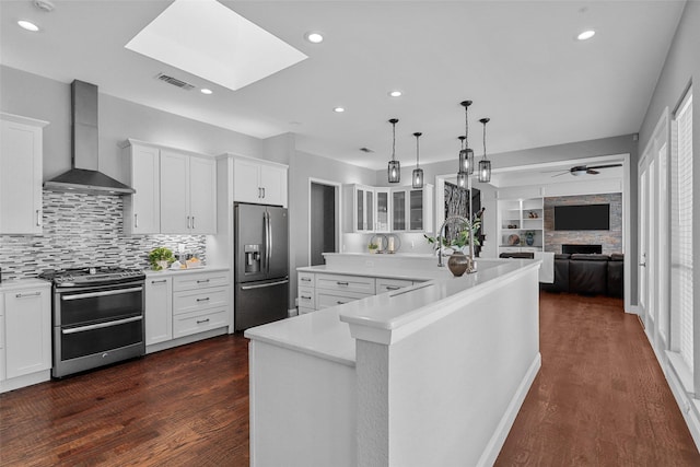 kitchen featuring a skylight, visible vents, wall chimney exhaust hood, appliances with stainless steel finishes, and light countertops