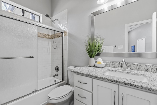 full bath featuring toilet, bath / shower combo with glass door, and vanity