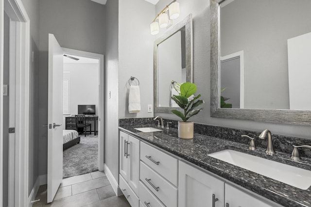 full bathroom featuring baseboards, double vanity, a sink, and tile patterned floors