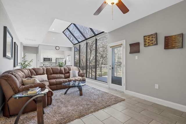 living room featuring a towering ceiling, light tile patterned floors, ceiling fan, and baseboards