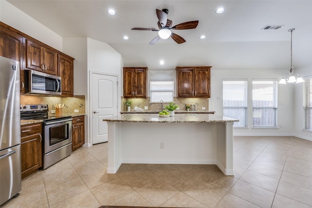 kitchen with a kitchen island, appliances with stainless steel finishes, vaulted ceiling, and light stone counters