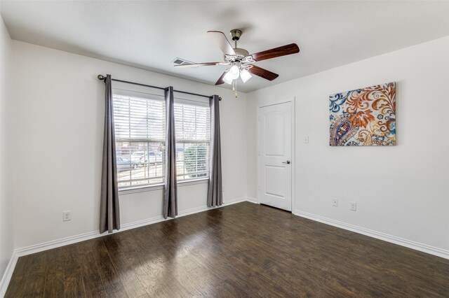 spare room featuring dark wood-style floors, ceiling fan, visible vents, and baseboards