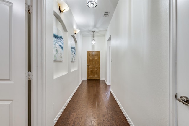 corridor with baseboards, visible vents, and dark wood-type flooring