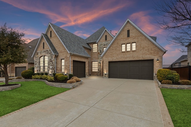 view of front of home with an attached garage, brick siding, fence, driveway, and a front lawn