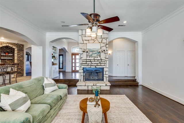 living room with baseboards, visible vents, wood finished floors, crown molding, and a fireplace