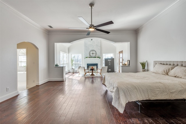 bedroom with crown molding, a fireplace, visible vents, and wood finished floors