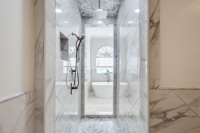 bathroom with a freestanding tub, a textured wall, tile walls, and a marble finish shower