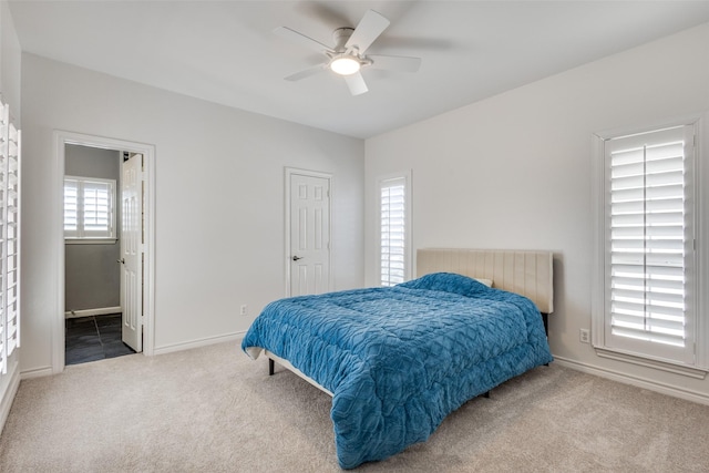 carpeted bedroom with ceiling fan, baseboards, and ensuite bathroom