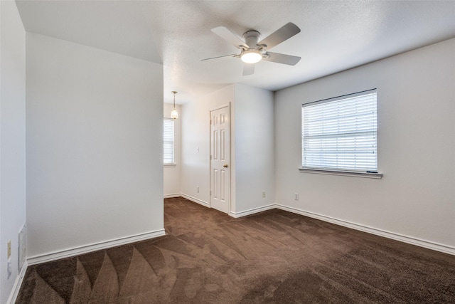 empty room featuring visible vents, dark carpet, baseboards, and ceiling fan