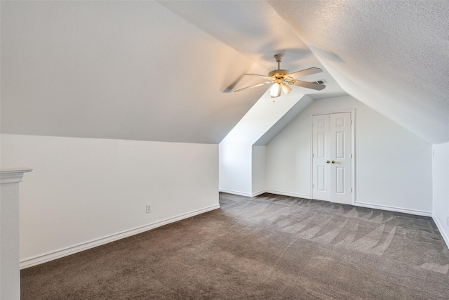 bonus room with baseboards, lofted ceiling, ceiling fan, dark colored carpet, and a textured ceiling