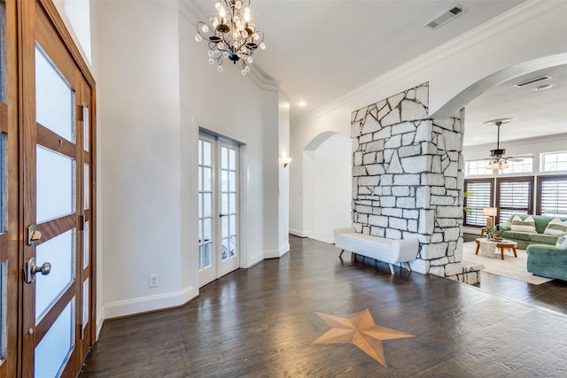 foyer with arched walkways, wood finished floors, visible vents, baseboards, and crown molding