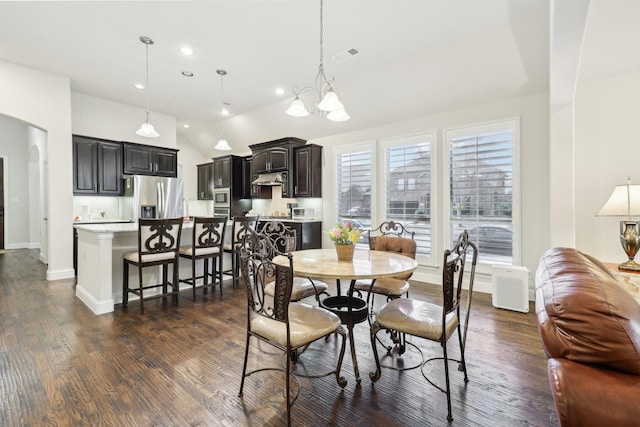 dining space with visible vents, arched walkways, dark wood-style floors, an inviting chandelier, and vaulted ceiling