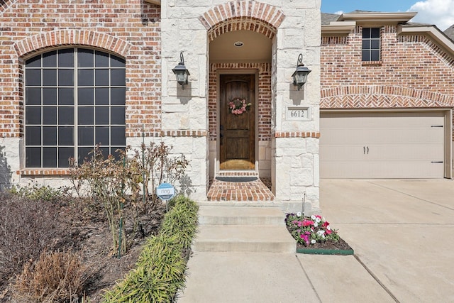 entrance to property featuring a garage, driveway, and brick siding