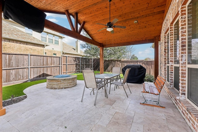 view of patio with an outdoor fire pit, ceiling fan, a fenced backyard, grilling area, and outdoor dining area