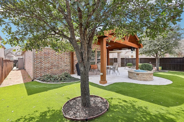 view of yard featuring a ceiling fan, an outdoor fire pit, a fenced backyard, and a patio