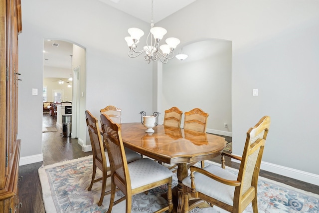 dining space featuring arched walkways, dark wood-type flooring, and baseboards