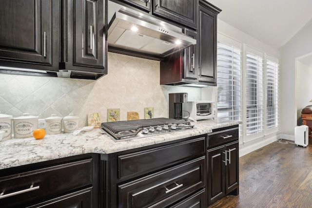 kitchen featuring stainless steel gas cooktop, decorative backsplash, dark wood-style flooring, and exhaust hood