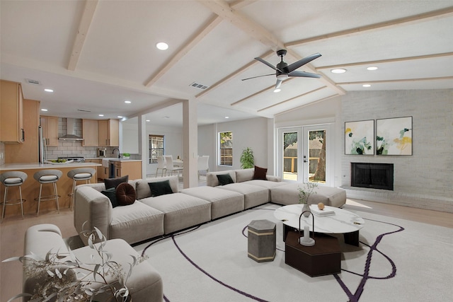 living area with vaulted ceiling with beams, a fireplace, visible vents, and french doors