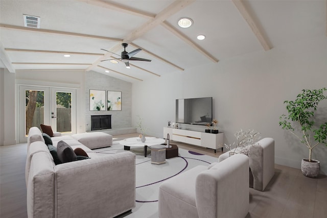 living area with vaulted ceiling with beams, a fireplace, wood finished floors, visible vents, and french doors