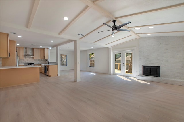 unfurnished living room with vaulted ceiling with beams, light wood-type flooring, visible vents, and a fireplace