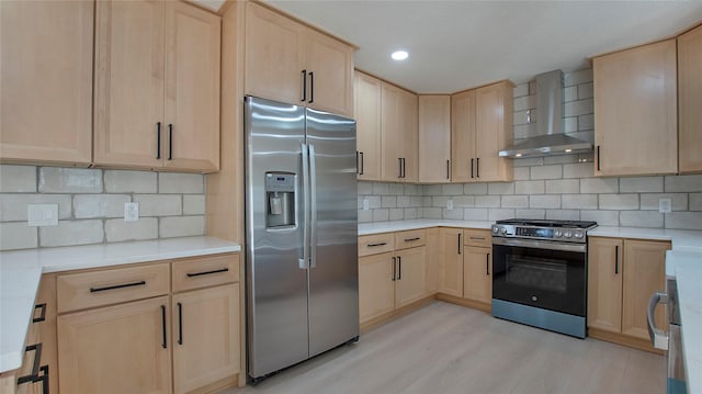 kitchen with wall chimney range hood, appliances with stainless steel finishes, light wood-style floors, and light brown cabinetry