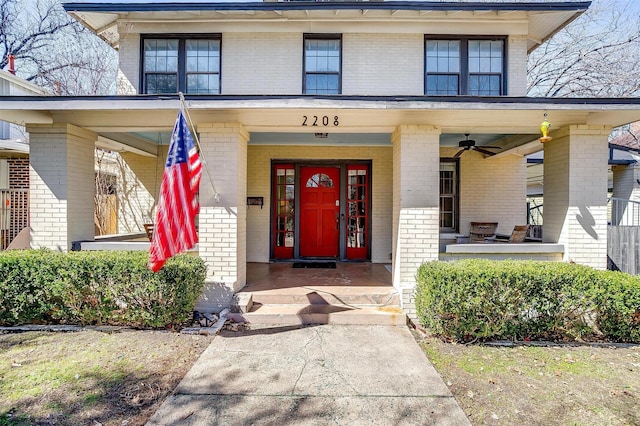 doorway to property with a porch and brick siding