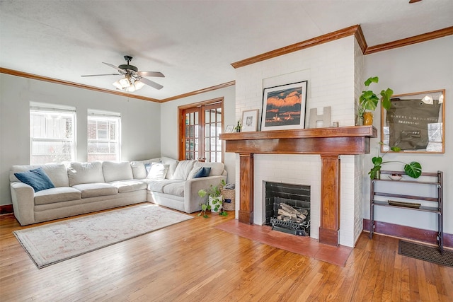 living room with a fireplace, crown molding, a ceiling fan, wood finished floors, and baseboards