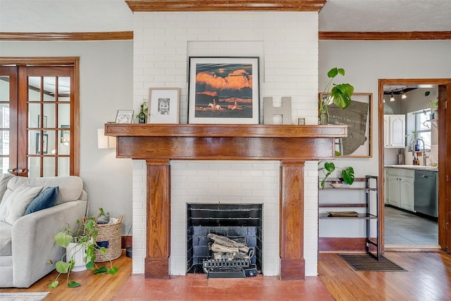 living room with a fireplace, ornamental molding, and wood finished floors