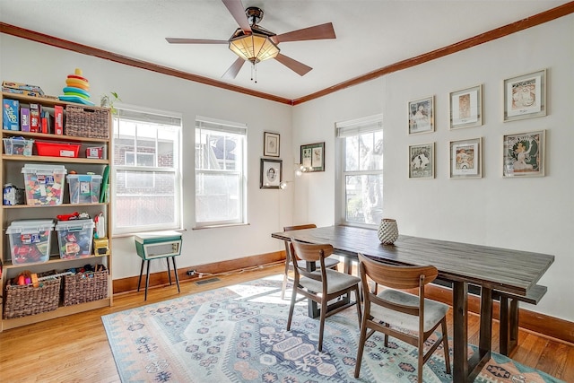 dining space with a ceiling fan, crown molding, baseboards, and wood finished floors