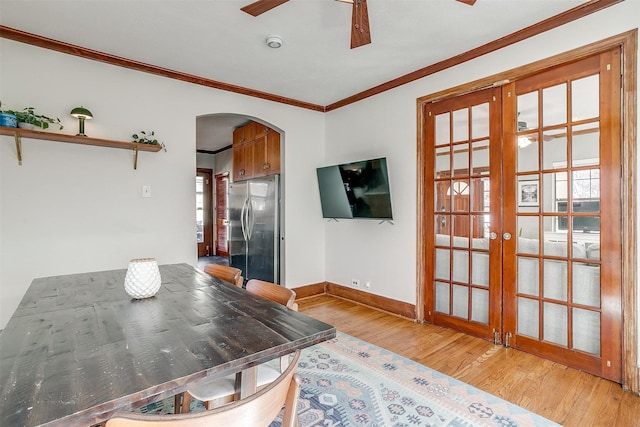 dining room featuring arched walkways, ceiling fan, wood finished floors, french doors, and crown molding